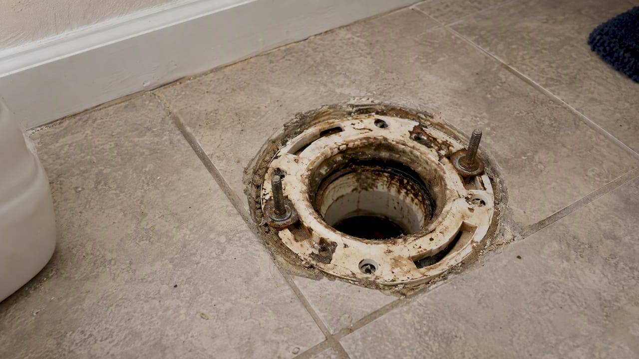 Exposed toilet flange beside surrounding floor